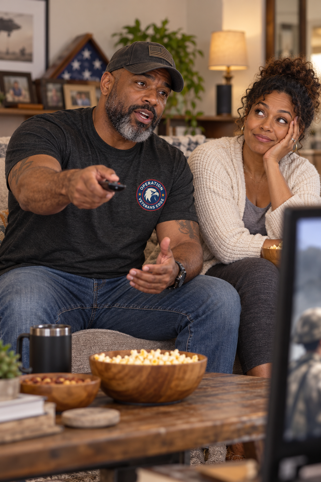 Illustrative lifestyle mockup: Black male veteran in an OVE tee pausing a military movie to explain an error.